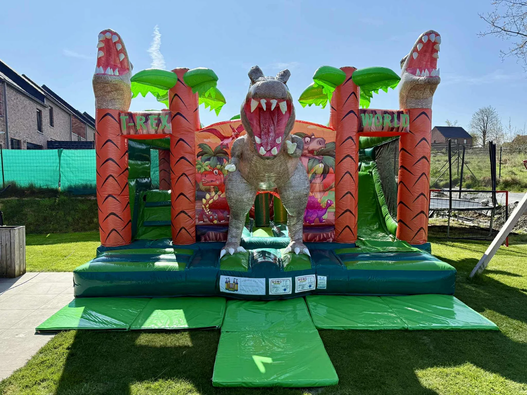 Château gonflable T-Rex installé dans un jardin